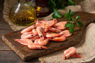 Shrimp on a wooden Board on a brown wooden table. Lots of prawns on the serving Board. Prawns close up