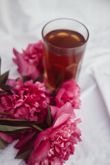 glass with tea and a bouquet of flowers on a white vintage background. flowers red peonies