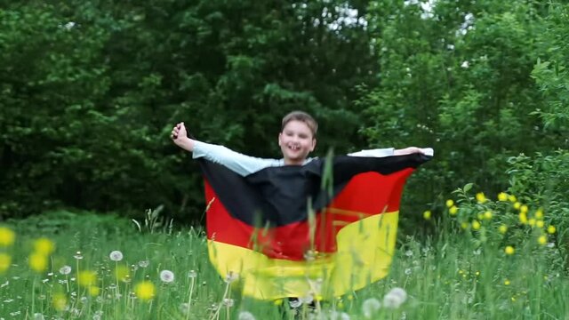 young kid boy waving running with national Germany flag outdoors - german flag, country, patriotism, celebrating German Unity Day October 3. children learning deutsch at foreign language camp courses.