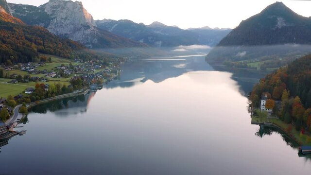 4k drone forward video (Ultra High Definition). Misty morning scene of Grundlsee lake. Stunning autumn view of Roslern village, Liezen District of Styria, Austria, Europe. 