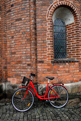 Fototapeta na wymiar Aarhus, Denmark A red bicycle leaning up against the cathedral.