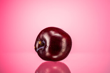 ripe red large plum on a red gradient background