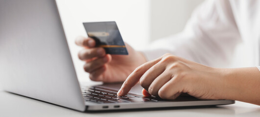 Hands holding credit card and using laptop computer, Businesswoman working at home, Online shopping, E-commerce, Spending money, Internet banking.