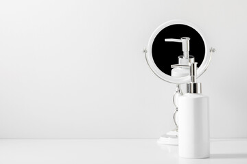 Soft light white bathroom decor, mirror, soap dispenser, accessories on white shelf. Elegant decor bathroom interior.