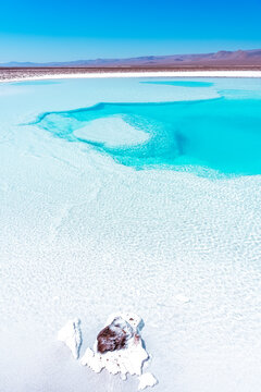 Crystal blue salt water lake pool with mountain range in the background on the horizon in the Atacama Desert in Chile