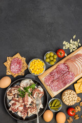 Bacon in pan, salami witchcraft on cutting board, vegetables, cookies.  Ingredients for english breakfast.