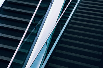 A repeated pattern of linear lines is part of an architectural feature of a modern stairwell in a public space. 