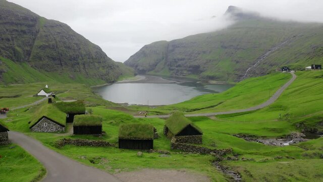 4k drone footage (Ultra High Definition). Green summer scene of Saksun village with typical turf-top houses and Saksunar Kirkja, Faroe Islands. Nice morning view of Streymoy island, Denmark, Europe.