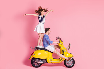 Fototapeta na wymiar Profile side view portrait of his he her she nice attractive cheerful cheery carefree childish careless couple riding moped girl standing flying having fun isolated on pink pastel color background