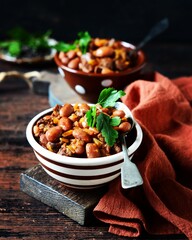 Beef stew with beans, tomatoes and vegetables on a dark wooden background