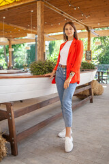 girl in jeans and a red jacket standing in a restaurant