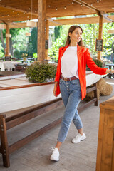 girl in jeans and a red jacket standing in a restaurant