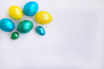 Yellow, blue and green easter eggs on a white background side view. Top view