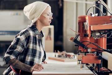 Woman carpenter working at joiner machine