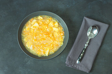 Chicken soup on black bowl on dark black stone table.