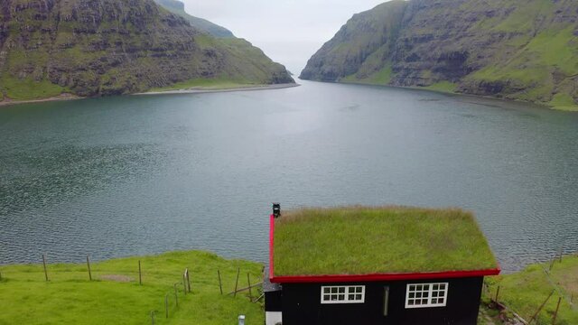 4k drone forward video (Ultra High Definition). Summer view of Saksun village with traditional turf-top house. Wonderful morning scene of Pollurin Laguna, Faroe Islands, Denmark, Europe.