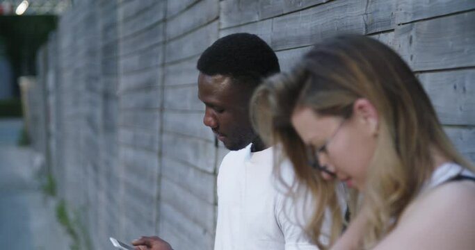 Man and Woman Looking at Phones Outdoors