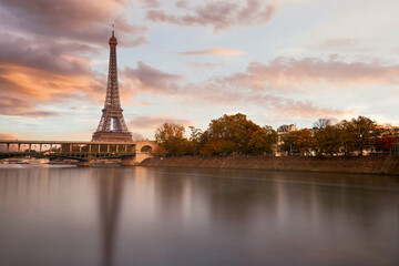 The eiffel tower at sunset from the other bank of the seine river and a view on the Bir Hakeim bridge