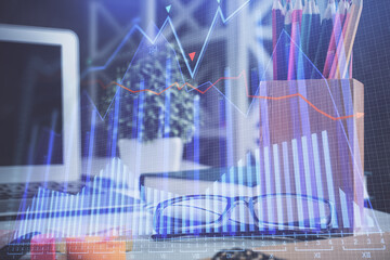 Financial chart hologram with glasses on the table background. Concept of business. Double exposure.