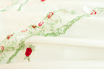 Red embroidered roses on white satin fabric