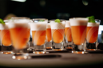 Close of many alcoholic shot-drinks with mint leaf on top