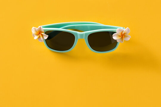 Sunglasses with flowers on yellow background. Copy space