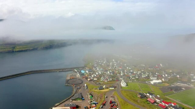 4k drone forward video (Ultra High Definition). Amazing morning cityscape of Eidi town. Beautiful summer view of Eysturoy island. Attractive seascape of Atlantic ocean, Faroe Islands, Denmark, Europe.