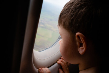 2 years old boy looking out from the window of the plane - rear view