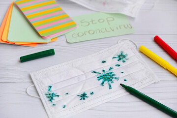 Close-up of a medical mask with a children's drawing of the virus molecule with colored felt-tip pens.
