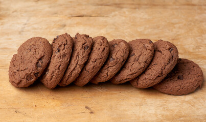stack of baked round chocolate chip cookies on a brown wooden table