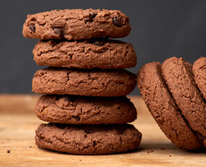 stack of baked round chocolate chip cookies on a brown wooden table