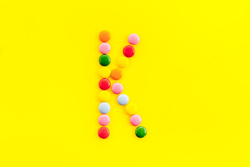 Letter K - alphabet made with sweets on yellow from above