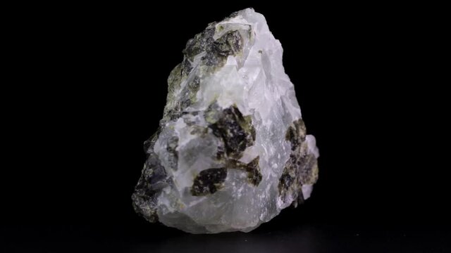 Rock of raw Prehnite mineral slowly rotating over a black background