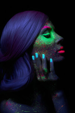 Fashion model woman in neon light bright fluorescent makeup, long hair, drop on face. Beautiful model pink hair girl colorful make-up, painted skin, body art design ultraviolet