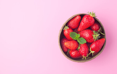 A bowl of fresh organic ripe strawberries with mint on pink background, top view. Healthy eating concept, copy space