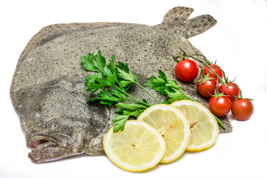 a raw turbot fish with lemon slices,cherry tomatoes and parsley isolated on white background