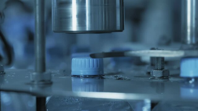 The automatic device spins the bottle cap. Automated line for the production of clean water in plastic bottles. Clean water bottles on.