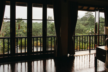 Empty balinese style room with large wwndows to the tropical garden.
