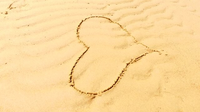 Draw a heart into the wet sand near the sea.