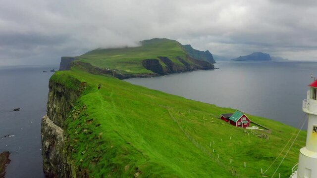 4k drone forward video (Ultra High Definition). Gloomy summer scene of Mykines island with old lighthouse. Wonderful morning view of Faroe Islands, Denmark. Dramatic seascape of Atlantic ocean.