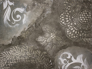 sample of factured plaster surface of the grey wall with floral ornament