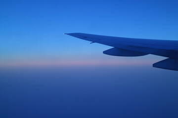 Wing of the airplane against beautiful blue morning sky during flight