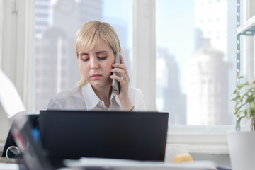 Young businesswoman talking on smartphone and working on a laptop