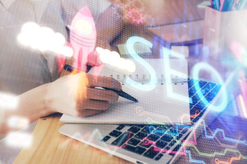 Multi exposure of woman's hands making notes with SEO icon. Concept of Search engine optimization