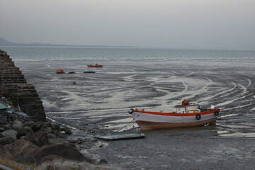 A fishing boat standing during the low tide near a ocean.