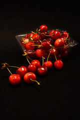 Container of fresh cherries on a black background.