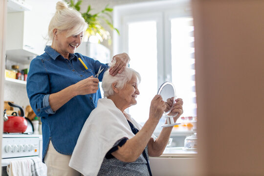 Woman cutting her elderly mother's hair at home
