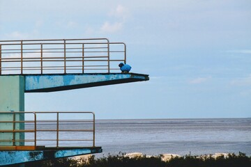 Blaues Schaf auf einem Sprungturm am Meer.