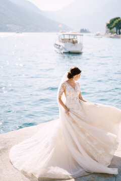 The bride in a wedding dress is dancing on the pier, waving a dress. Fine-art wedding photo in Montenegro, Perast.