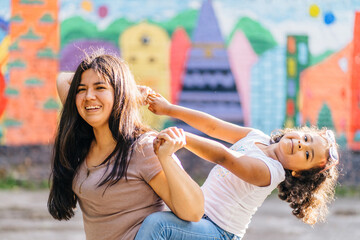 Latin american mother playing with her small dark skinned hispanic daughter outdoor, in summer...
